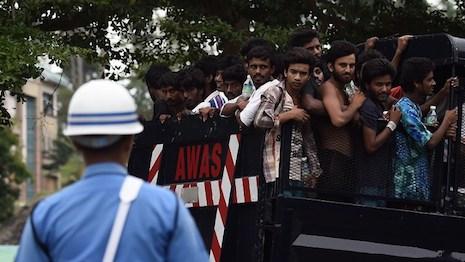 A member of the Malaysian Navy stands guard as a truck carrying Bangladeshi and Rohingya migrants arrives at a naval base in Langkawi Wednesday so they can be transferred to a mainland immigration depot.