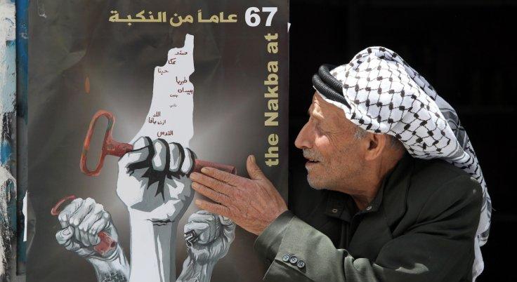 A Palestinian man touches a poster displayed on a door announcing the Nakba commemorations on May 14, 2015, at the al-Fawar refugee camp in the West Bank town of Hebron.