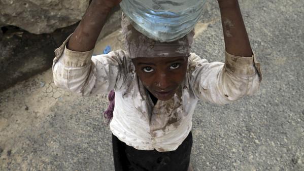 An internally displaced girl carries water on her head in the district of Khamir of Yemen's northwestern province of Amran.