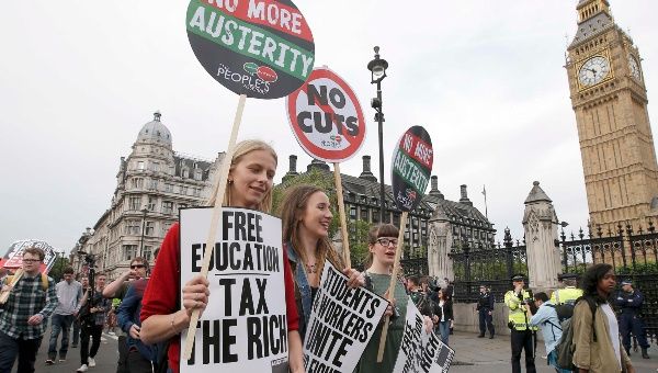 Demonstrators hold up placards as they march through Westminster during protest after the State Opening of Parliament in central London.
