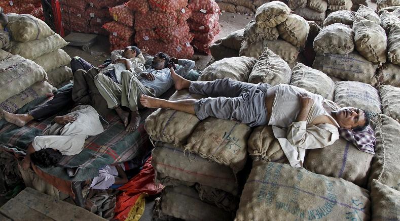 Vendors take a nap on stacked sacks of vegetables at a wholesale market on a hot summer day in Chandigarh, India, May 29, 2015.