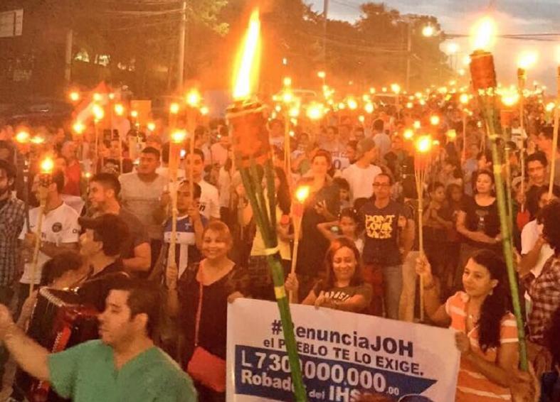 Protesters carry torches and signs that read 