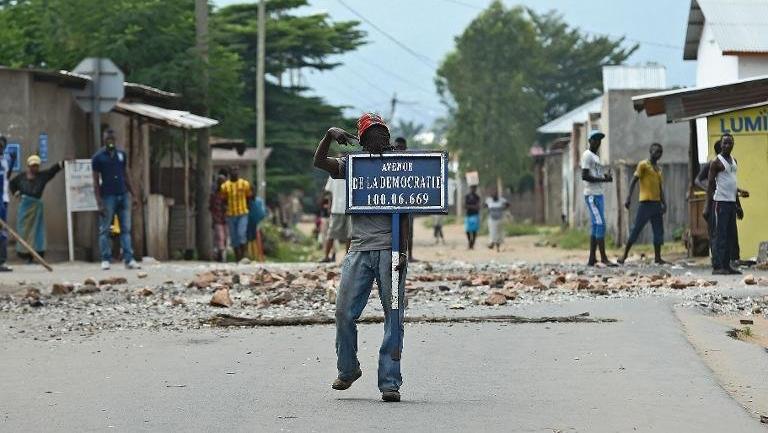 A protester opposed to Burundian President Pierre Nkurunziza's third term holds a road sign reading 'Avenue of Democracy ' during a demonstration in Bujumbura, May 26, 2015.