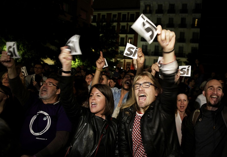 Supporters of Podemos react at the party's meeting area after the regional and municipal elections in Madrid
