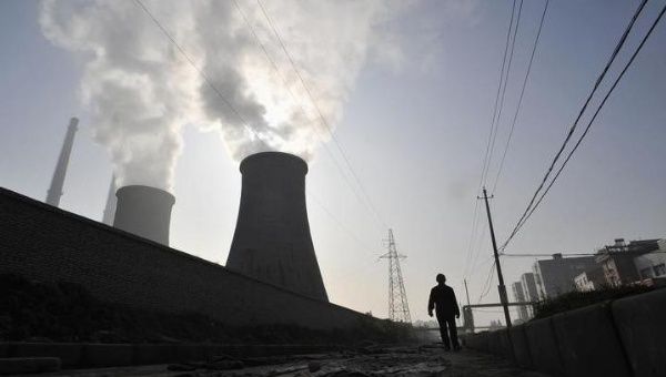 A man walks past a coal-burning power plant in Xiangfan, Hubei province Nov. 19, 2010.