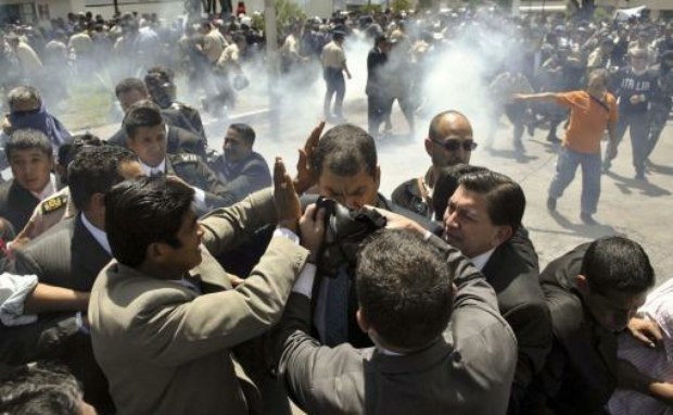 People put a gas mask on President Correa as a police rebellion over labor issues transformed into a violent revolt.