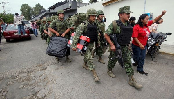 A member of the CNTE yells while walking alongside soldiers after they were forced to leave the INE premises in Oaxaca, June 2, 2015