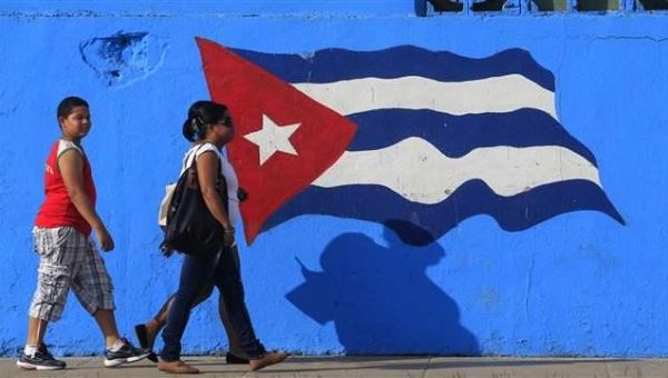 People walk beside a Cuban flag painted on a wall in Matanzas in central Cuba.