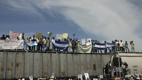 Migrants holding Guatemalan and Honduran flags ride on the freight train known as 