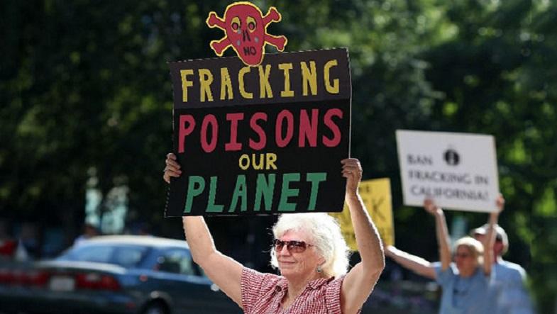 Protestors hold signs against fracking during a demonstration.
