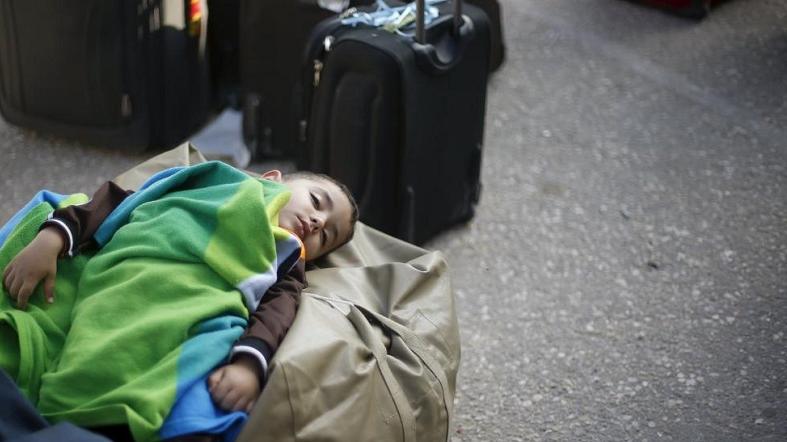 A Palestinian boy sleeps as he waits with his family for a travel permit to cross into Egypt, at the Rafah border crossing between Egypt and the southern Gaza Strip, June 13, 2015.
