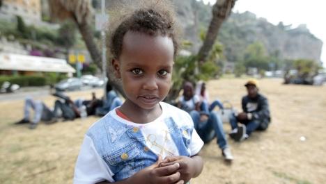 A child waits with migrants at the border between Italy and France in the city of Ventimiglia, Italy.