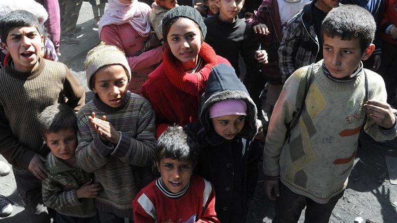 Children from Syria's besieged Yarmuk Palestinian refugee camp, south of Damascus, standing during a relief operation in February, 2014.
