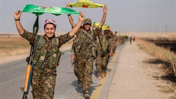 Kurdish fighters carry their parties' flags after claiming victory in Tel Abyad.