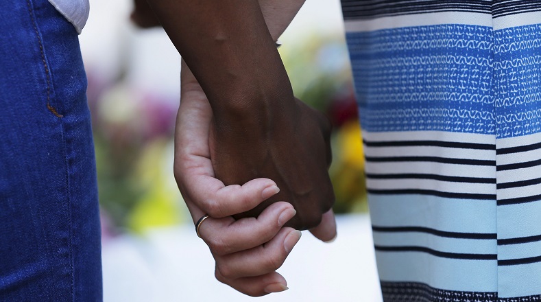 Mourners hold hands outside the Emanuel African Methodist Episcopal Church in Charleston, South Carolina, June 18, 2015 a day after a mass shooting left nine dead during a bible study at the church.