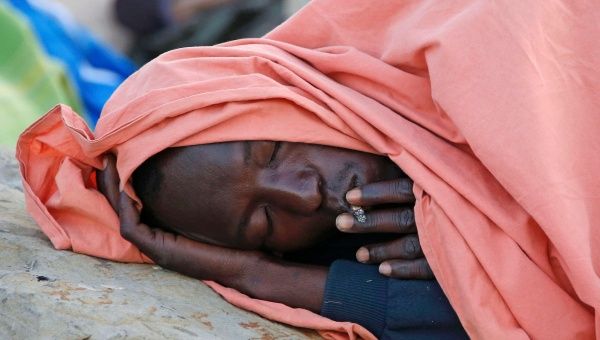 A migrant rests under a blanket at the Saint Ludovic border crossing on the Mediterranean Sea between Vintimille, Italy and Menton, France, June 17, 2015. 