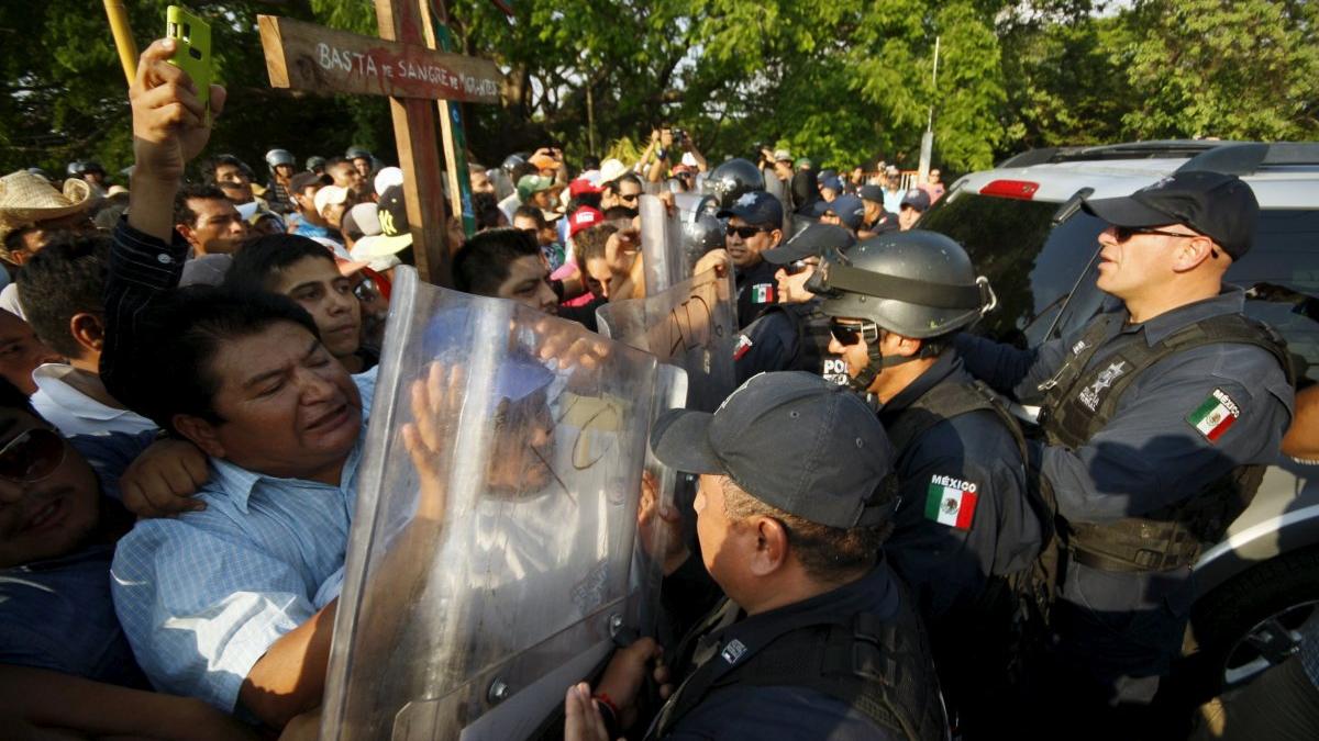 Migrants scuffle with riot police during their annual human rights protest amidst a crackdown on Central American citizens crossing overland towards the United States, in El Espinal April 15, 2015. The writing on the cross reads 