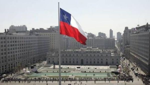 A giant Chilean flag is hoisted in front of the Government Palace in Santiago.