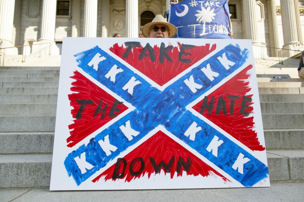 Jay Bender holds a sign asking for the removal of the confederate battle flag that flies at the South Carolina State House in Columbia, SC June 20, 2015.