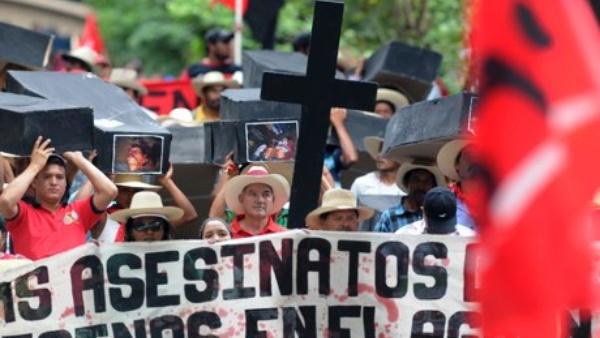Members of the Peasant Unified Movement of Aguán carry mock coffins bearing pictures of people murdered in land clashes during a march in Tegucigalpa.