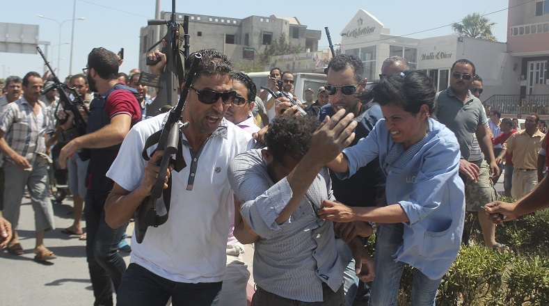 Police officers control the crowd while surrounding a man (front C) suspected to be involved in opening fire on a beachside hotel in Sousse, Tunisia, June 26, 2015.