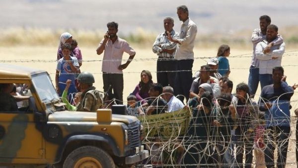 Syrian Kurds from Kobani wait behind the border fences to cross into Turkey on Friday.