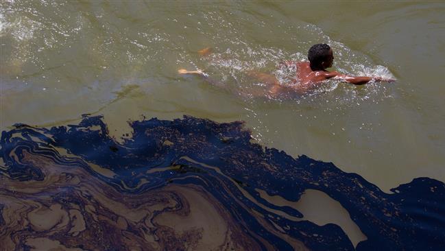 Handout picture released by the Colombian Ombudsman press office on June 12, 2015, shows a boy swimming next to an oil slick in the municipality of Tumaco, Colombia.