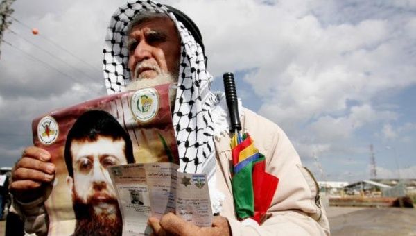 The father of Palestinian prisoner Khader Adnan holds a poster of his son, 19 February 2012.