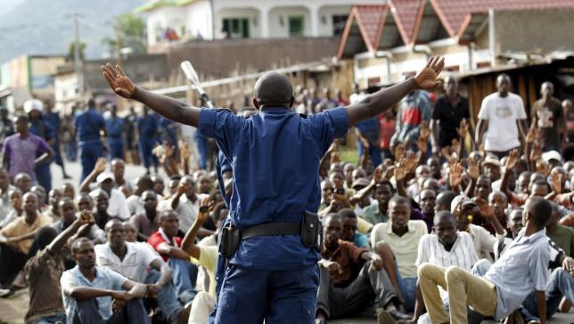 A riot police officer speaks to residents participating in street protests against the decision made by Burundi's ruling party to allow President Pierre Nkurunziza to run for a third term.