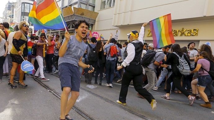 Activists run as riot police use a water cannon to disperse them before the Gay Pride Parade