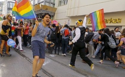 Activists run as riot police use a water cannon to disperse them before the Gay Pride Parade 