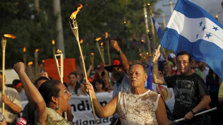 People take part in a march to demand the resignation of Honduran President Juan Hernandez in Tegucigalpa on June 26, 2015.