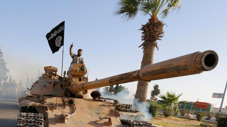 Fighters tied to the Islamic State group ride a tank as part of a military parade along the streets of northern Raqqa province, Syria, June 30, 2014.