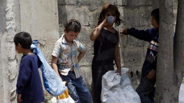 Syrian refugee children collect plastics as they stand along a street in south of Sidon, southern Lebanon, June 10, 2014.