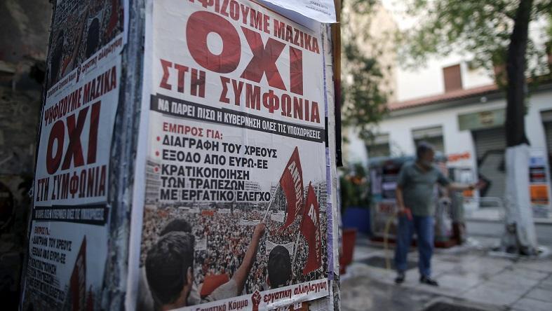 A man cleans the pavement behind a wall on which posters showing the word 'No' in Greek are affixed in Athens, Greece, July 2, 2015.