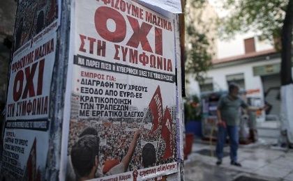 A man cleans the pavement behind a wall on which posters showing the word 'No' in Greek are affixed in Athens, Greece, July 2, 2015.