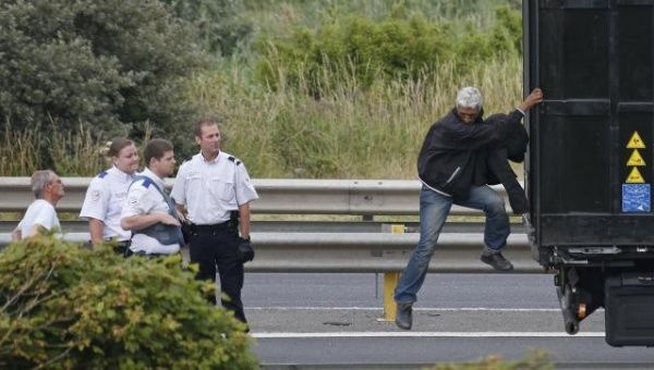 French policemen ask a migrant to get out of the trailer of a truck he climbed in, during an attempt to make a clandestine crossing to England through the Channel tunnel.