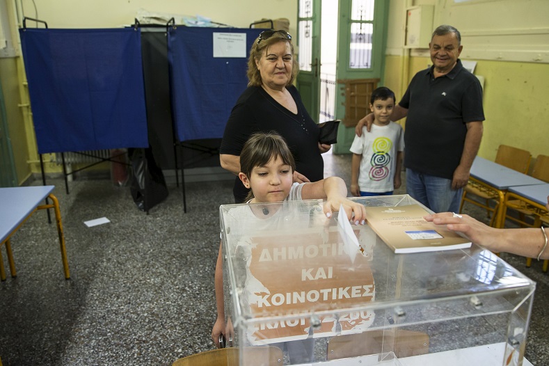 A child casts her grandmother's ballot during a referendum vote in Athens, Greece, July 5, 2015.