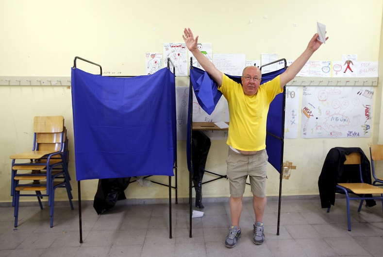 A man raises his arms as he leaves a polling booth before casting his ballot during a referendum vote in Athens, Greece, July 5, 2015.