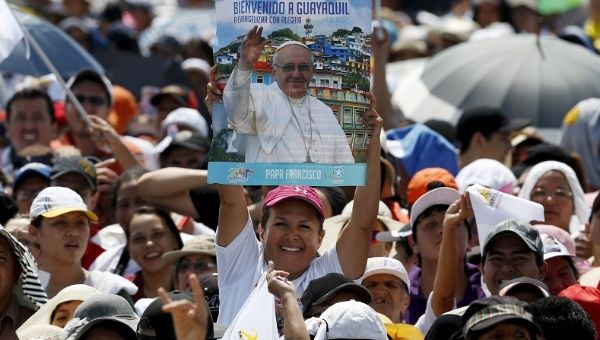 A woman holds a poster with a photograph of Pope Francis that reads 