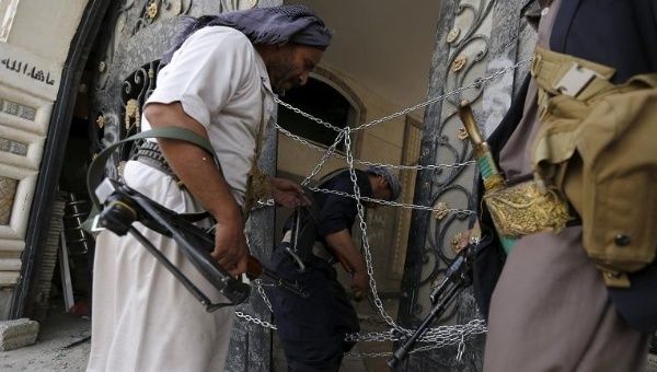 Guards walk through a damaged gate to a house bombed by Saudi-led air strikes in Yemen's capital Sanaa July 6, 2015.
