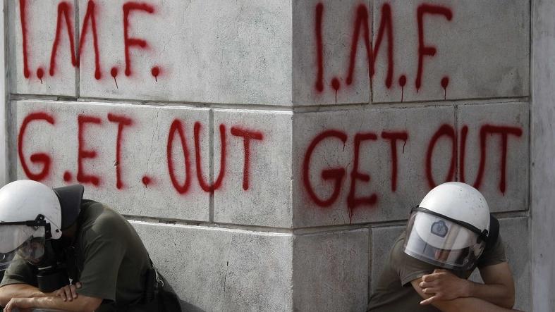 Greek riot policemen rest in front of graffiti written on the wall of a bank during demonstrations over austerity measures in Athens, May 5, 2010.