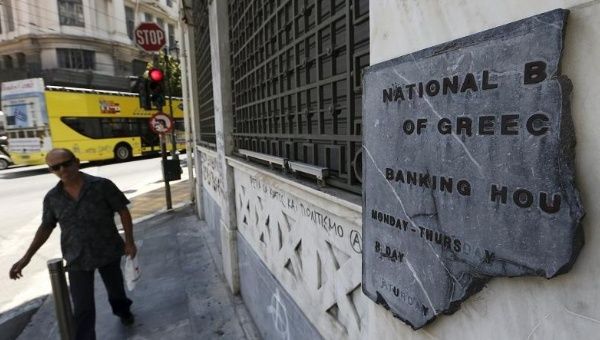 A Greek man walks by a broken marble National Bank sign outside a branch in Athens July 8, 2015.