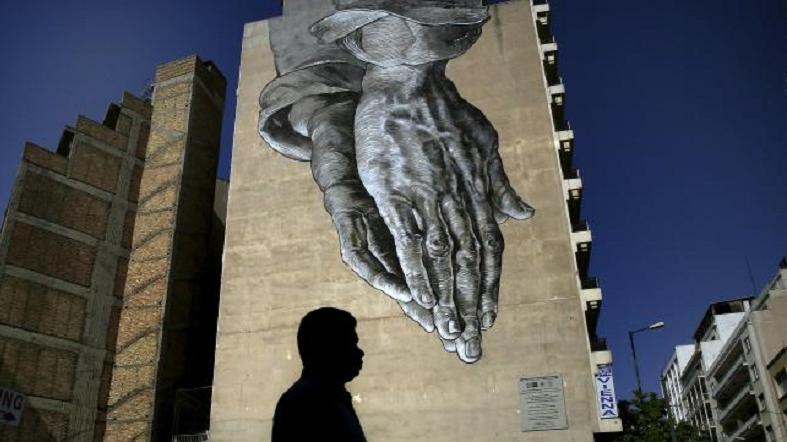 A pedestrian walks through empty streets by a mural in Athens, Greece July 12, 2015.