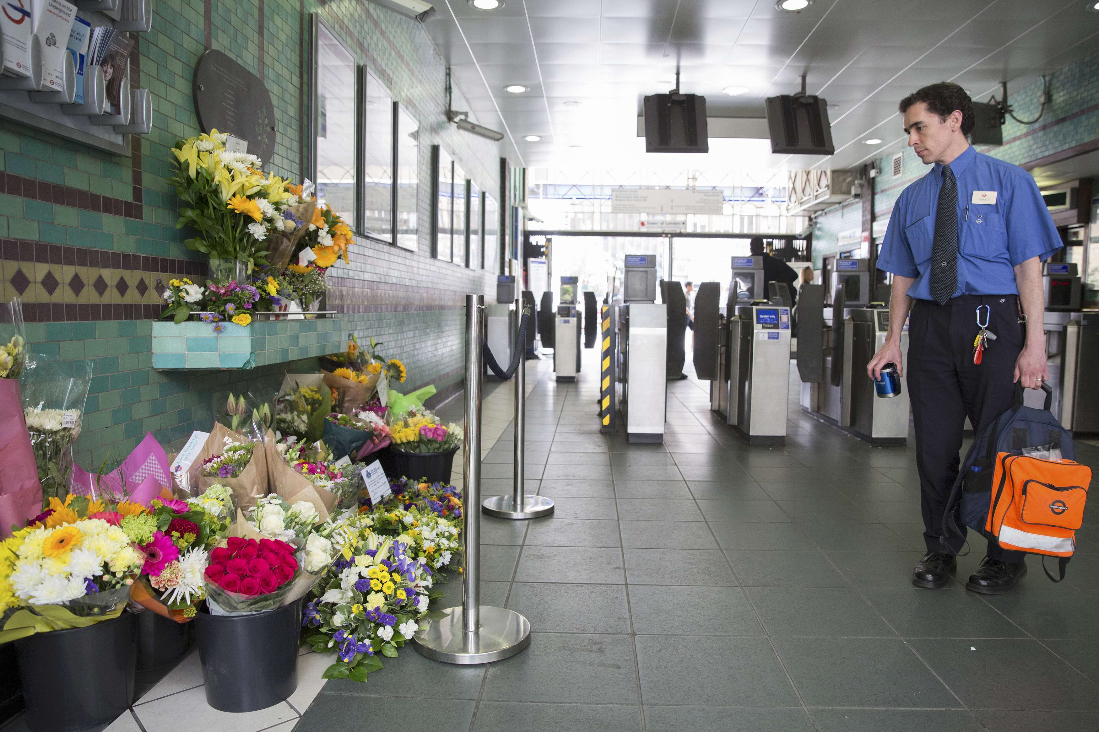 A tube worker looks at floral tributes for victims of the July 7, 2005 London bombings at Aldgate Station in London, Britain July 7, 2015.