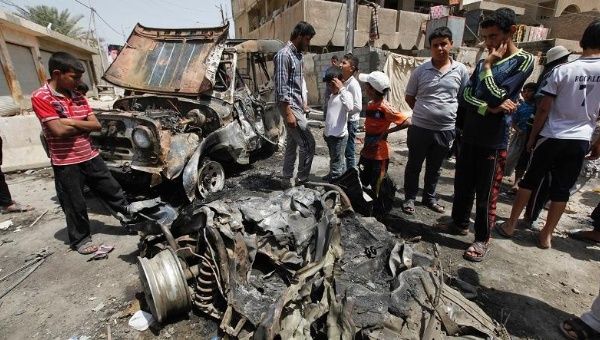 Residents gather at the site of an earlier, less deadly car bombing in Baghdad, Iraq.