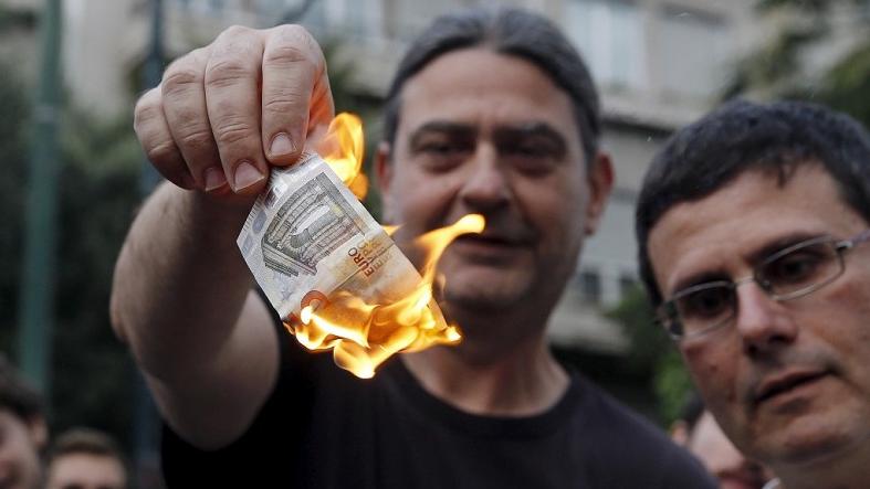Anti-austerity protesters burn a euro note during a demonstration outside the European Union (EU) offices in Athens, Greece June 28, 2015.
