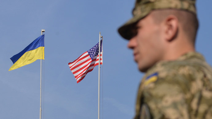 A Ukrainian soldier stands in front of the flags of Ukraine and the US