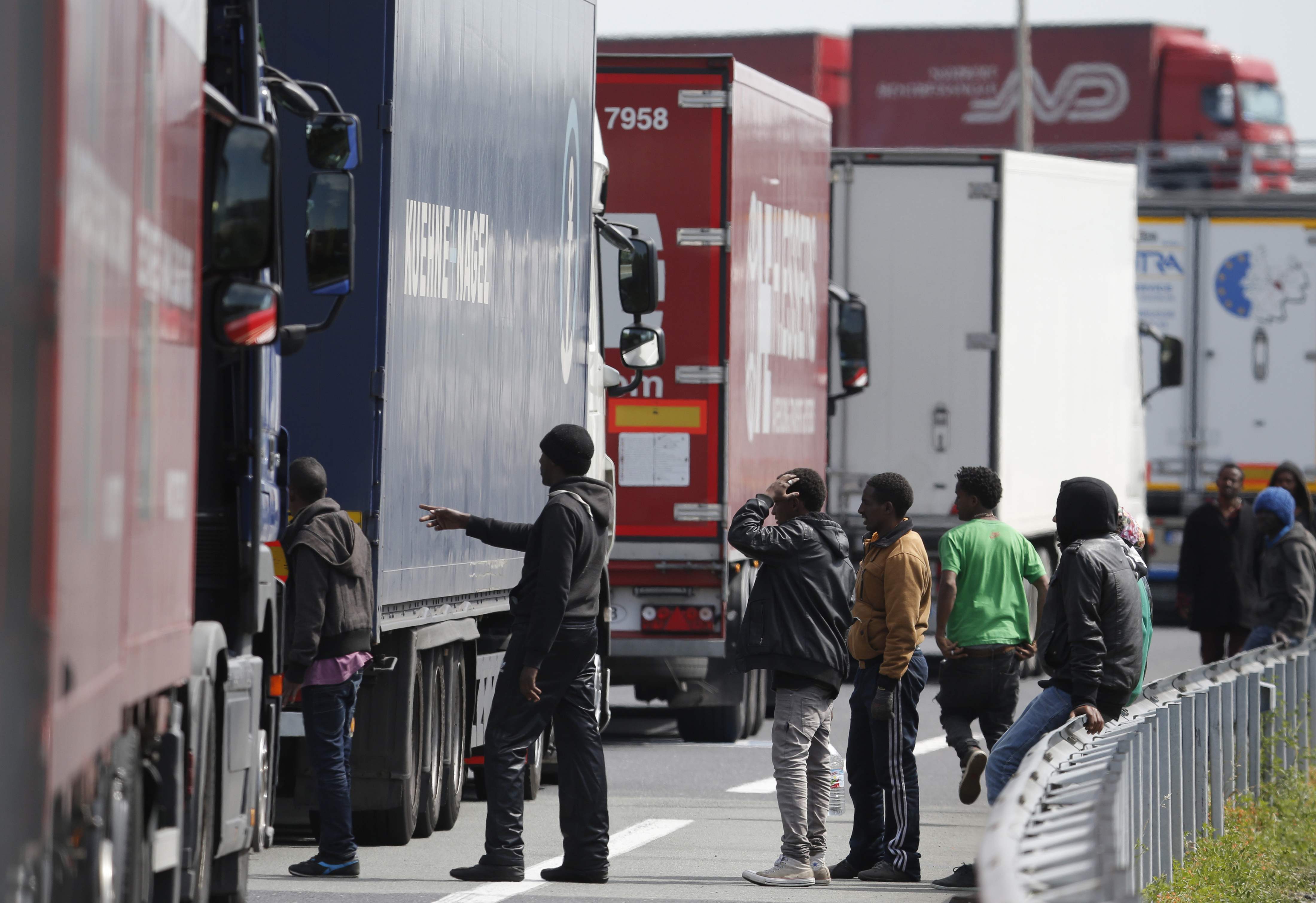 A group of migrants gather near a line of lorries waiting on the motorway which leads to the Channel Tunnel terminal in Calais, northern France, June 24, 2015.
