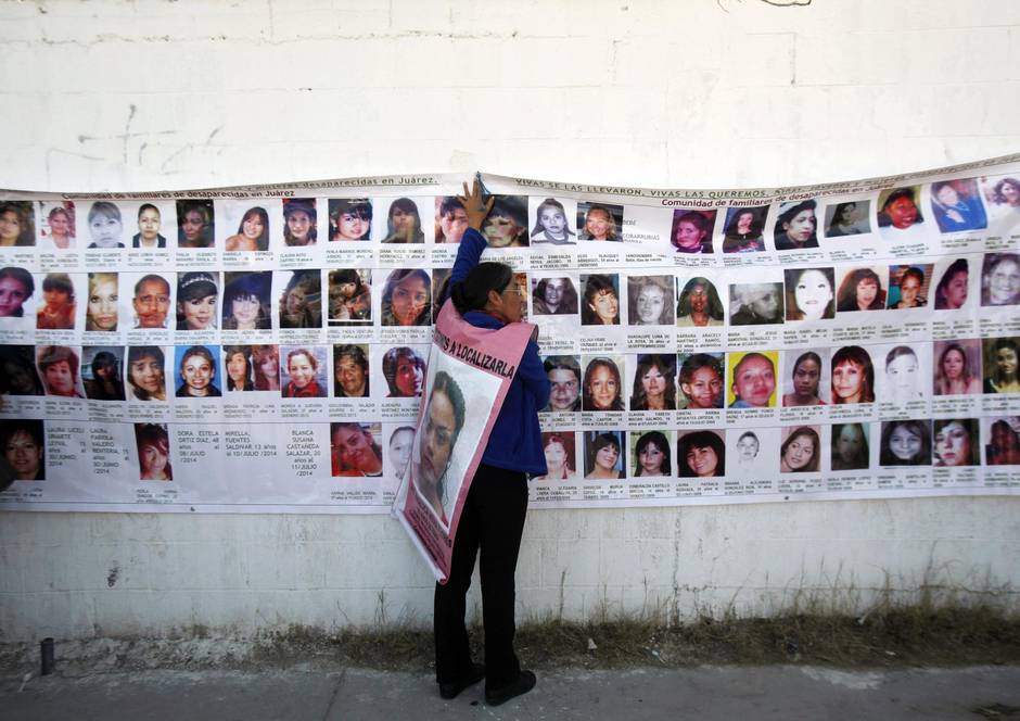 A woman holds onto a banner with the photographs of missing women in Ciudad Juarez